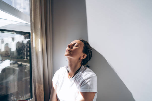 Woman pausing by a window, representing emotional exhaustion, people-pleasing, and burnout therapy in Ottawa and online across Ontario.